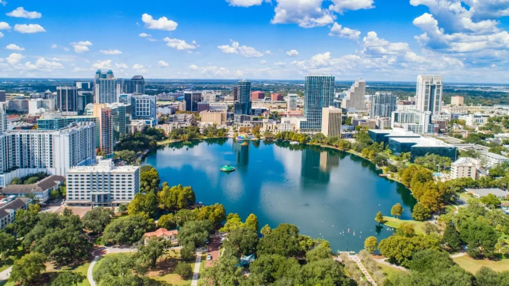 High-rise buildings in downtown Orlando lit up at dusk with a swan swimming on Lake Eola in the foreground