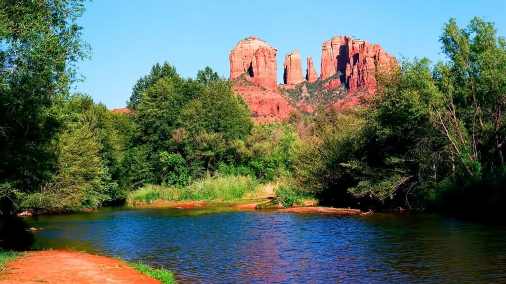 Cathedral Rock red sandstone formation at sunset in Sedona, Arizona, surrounded by green juniper trees
