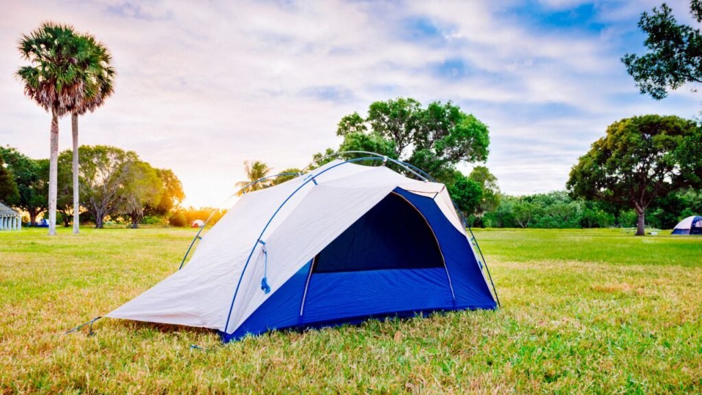 Camping tent set up in a Florida park at golden hour with palm trees and sunlight in the background