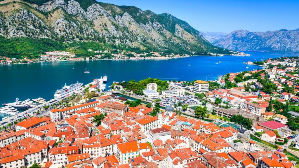 Aerial view of Kotor Old Town and the Bay of Kotor, Montenegro, with red-roofed buildings surrounded by dramatic limestone mountains