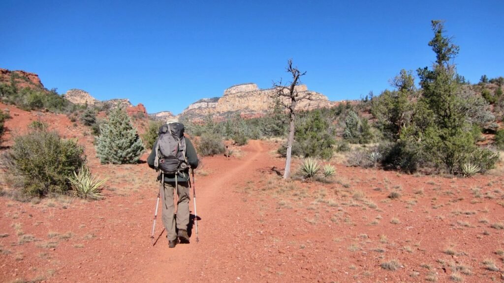 Backpacker hiking Long Canyon Trail in Coconino National Forest, Sedona, Arizona with red rock cliffs