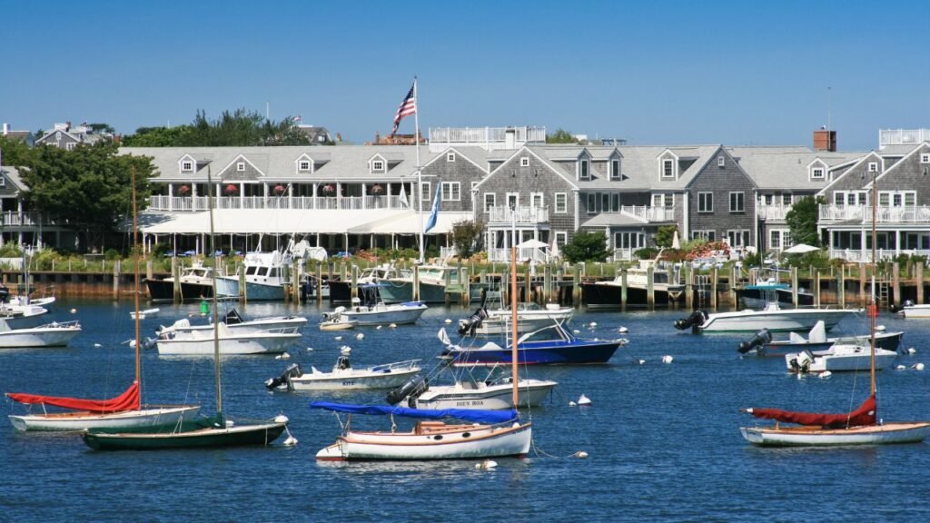 Fishing boats and yachts docked at a marina in Nantucket, Massachusetts, with gray shingled buildings