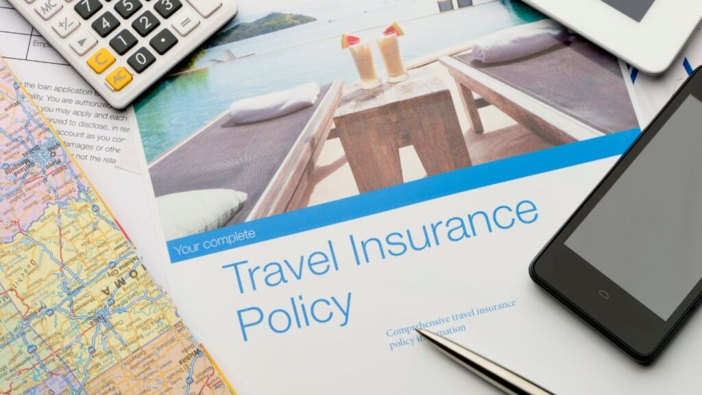 Travel insurance policy document on a desk with a calculator, smartphone, and map