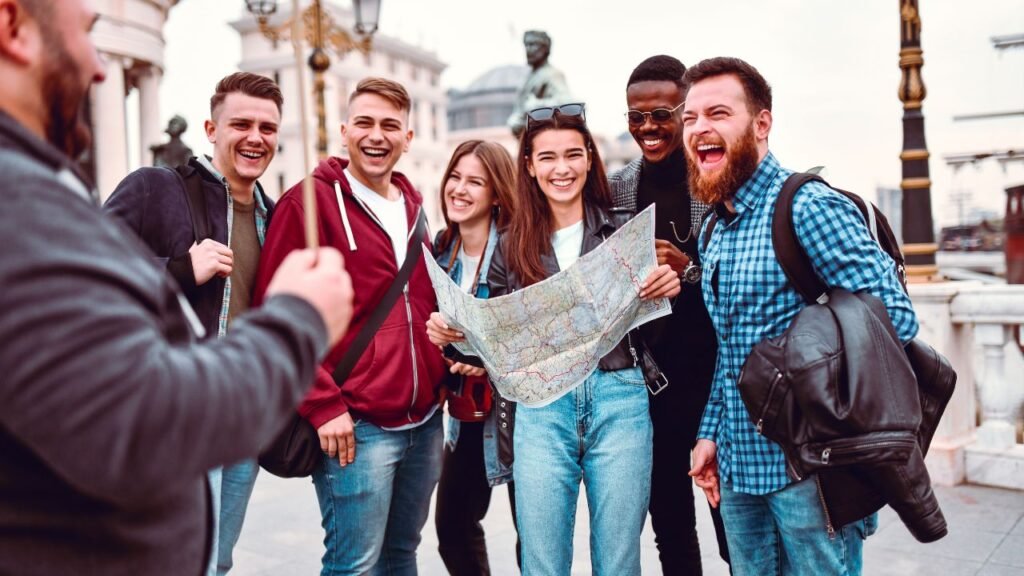 "Group of smiling tourists following a guide and checking a city map on a walking tour