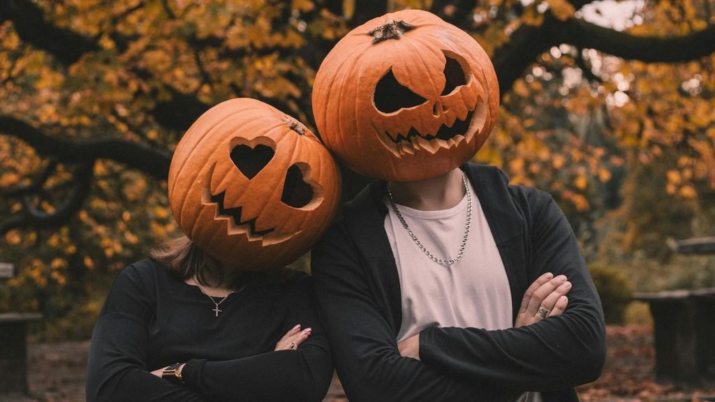 Illustrated spooky pumpkin patch with glowing jack-o'-lanterns, bare trees, and a full moon at dusk