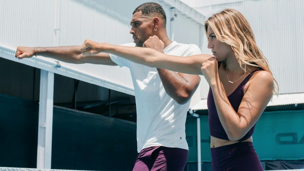 Man and woman in athletic wear throwing punches during an outdoor boxing workout