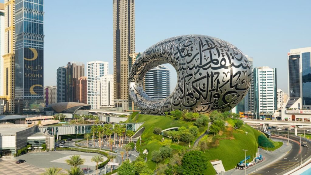 The oval-shaped Museum of the Future building with Arabic calligraphy on its facade, set on a green mound with Dubai skyscrapers behind it.