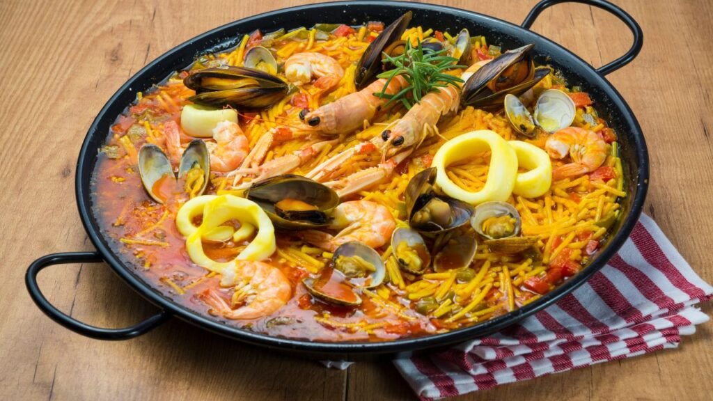 Traditional Valencian seafood paella with shrimp, mussels, clams, and squid in a black pa