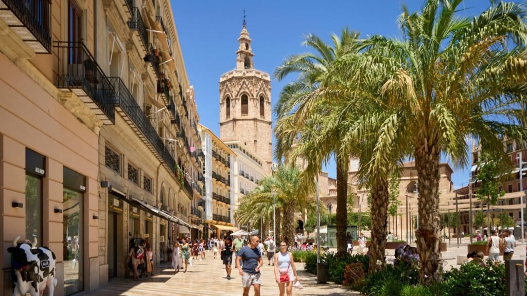 Pedestrian street lined with palm trees leading to the Micalet bell tower of Valencia Cathedral