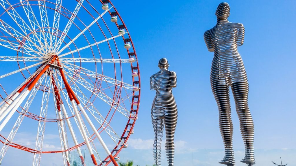 Close-up of the moving Ali and Nino metal statue with Ferris wheel behind it in Batumi