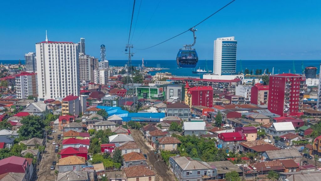 Cable car gondola gliding over Batumi's old town rooftops with the Black Sea and city towers in the background